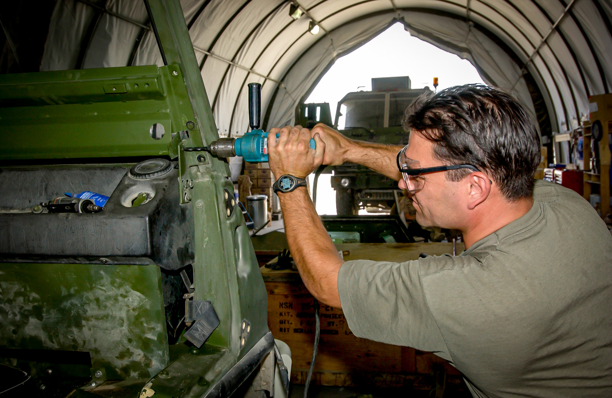 Soldier Repairing Vehicle in Weatherhaven Workshop